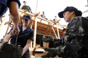 Specialist 2nd Class Jessica Helms, assigned to the US 7th Fleet staff embarked aboard the amphibious command ship USS Blue Ridge, passes a bucket of concrete to a sailor from the Armed Forces of the Philippines Navy. (USN)